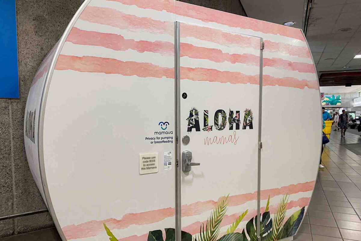 Private Mamava pod in a the Honolulu airport with “Aloha mamas” and “Privacy for pumping or breastfeeding” on the door, highlighting a quiet space for feeding a baby while traveling.
