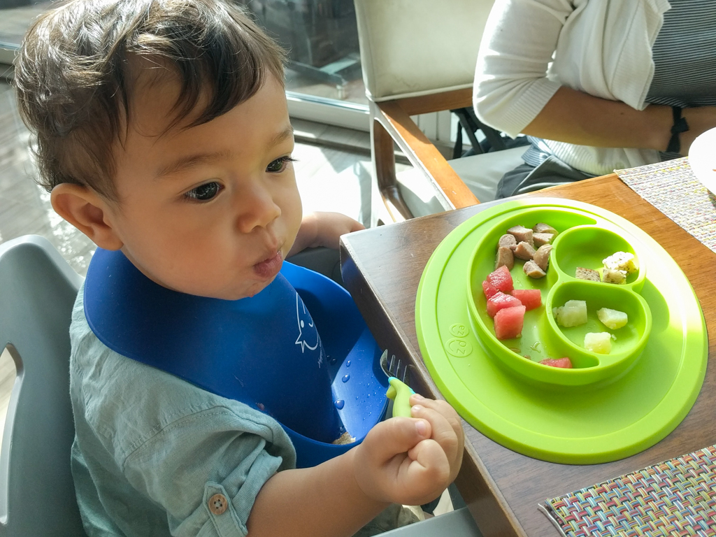 Toddler baby feeding himself on a trip to Dubai