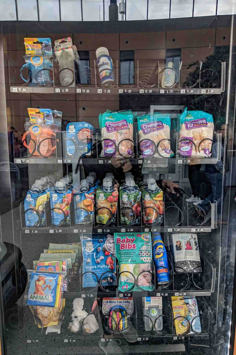 Vending machine at Hartford, Connecticut BDL airport filled with baby essentials like formula, bottles, snacks, and “Disposable Baby Bibs,” offering convenient solutions for parents to take of a baby while traveling.