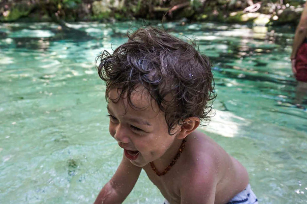 Toddler standing and splashing in the cenote