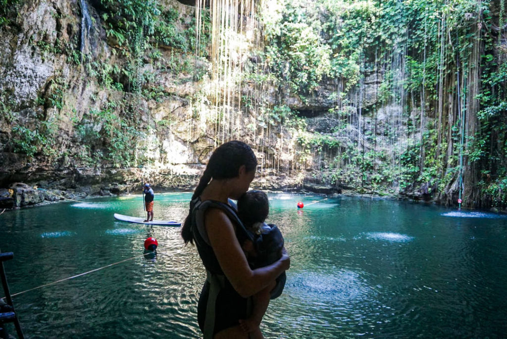 Mom holding baby looking at cenote underground pool