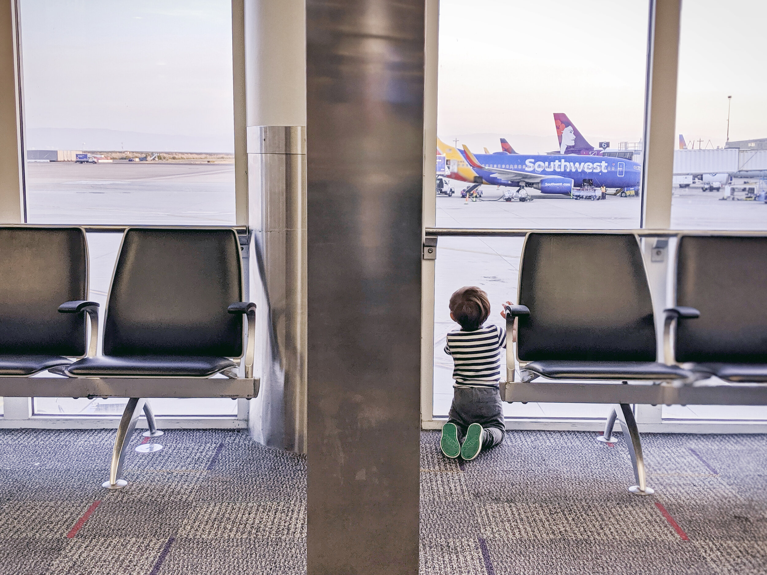 https://www.famileetravel.com/wp-content/uploads/2019/11/Baby-kneeling-airport-gate-watching-planes-Southwest-Hawaiian.jpg