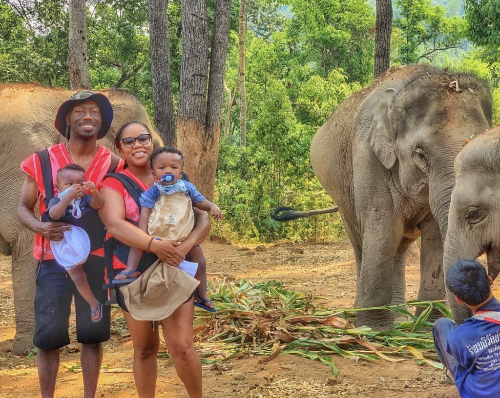 Young Black family with twins traveling in Thailand seeing elephants - diversity in family travel