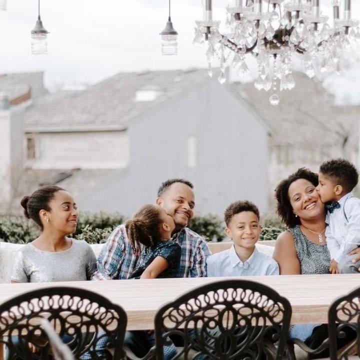 Black family with 4 kids sitting at table smiling