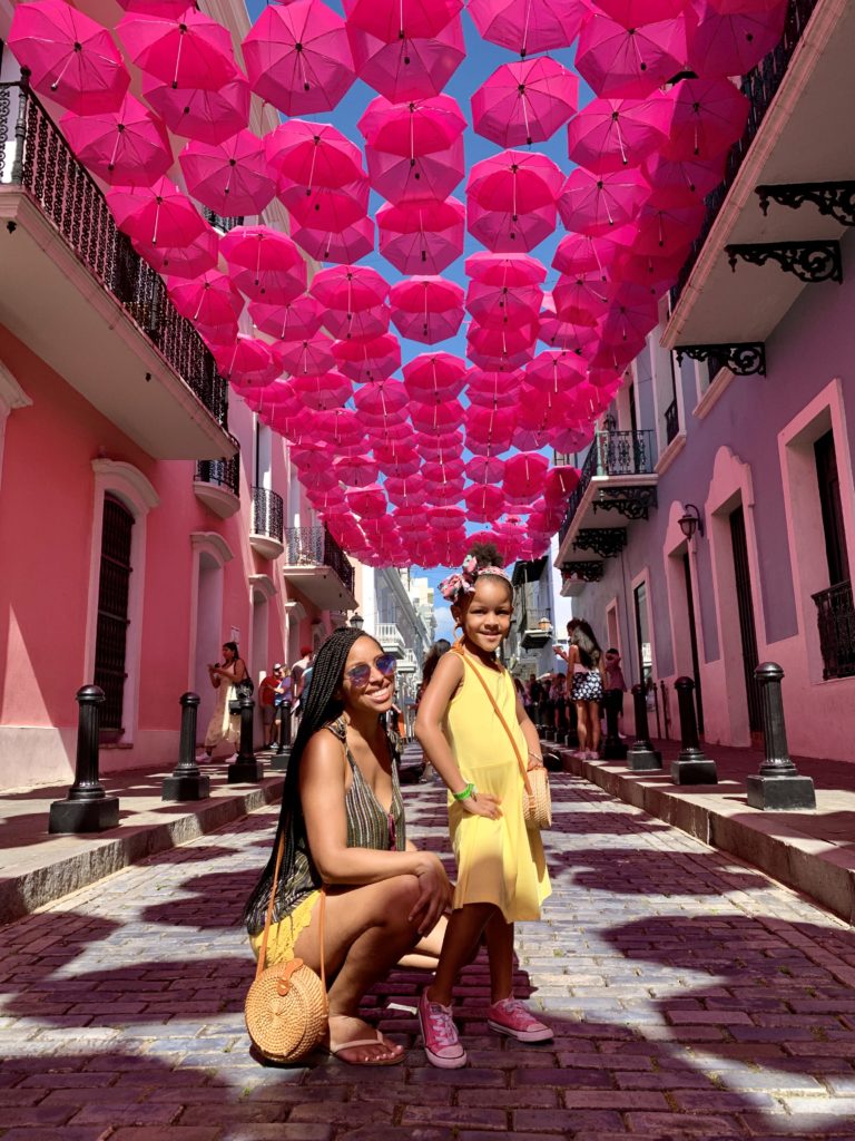Mom and daughter under pink umbrella street traveling - diversity in family travel