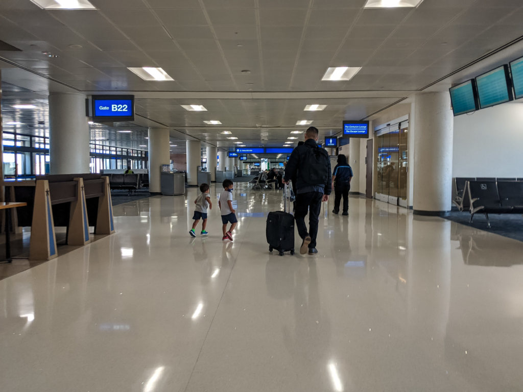 Dad with suitcase with two young kids - flying with a toddler in a pandemic