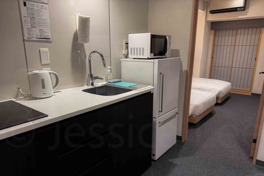 A family‑friendly two‑bedroom apartment in the Mimaru Namba Station hotel with a kitchenette, fridge, freezer, microwave, tea kettle, and sink and 1 bedroom area is visible — practical for multi‑day stays and families with kids.