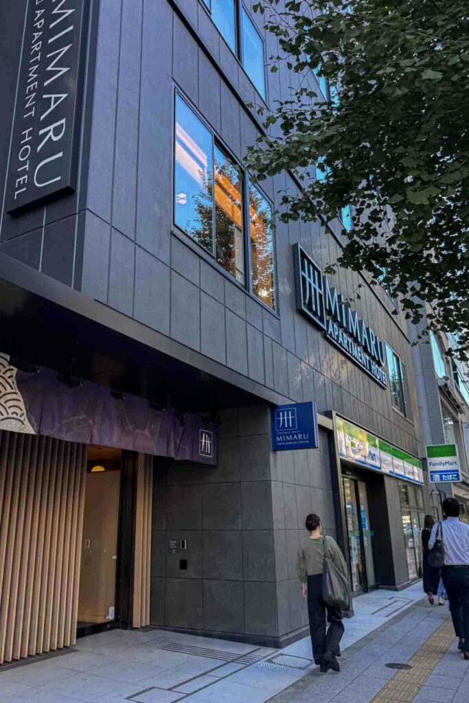 Street view of the Mimaru Tokyo Asakusa Station Apartment Hotel entrance with signage and a FamilyMart below. Prime location near transit and shops, perfect for families.