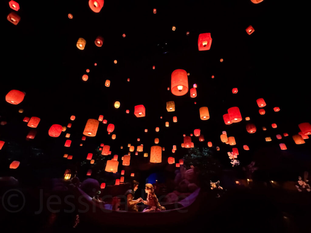 A magical lantern scene inside a dark ride at Tokyo DisneySea, with warm glowing orange lights floating above Rapunel and Flynn in a boat. One of the most enchanting kids rides in Tokyo.