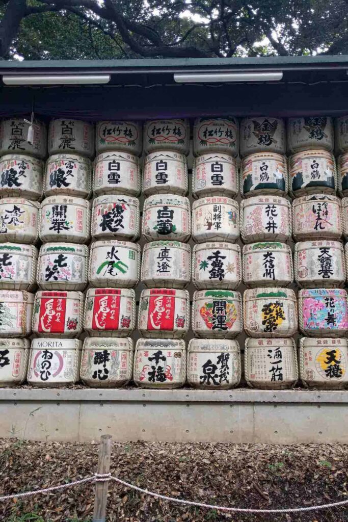 A grid of colorful sake barrels with Japanese writing flank the entrance path to the Meiji Shrine.