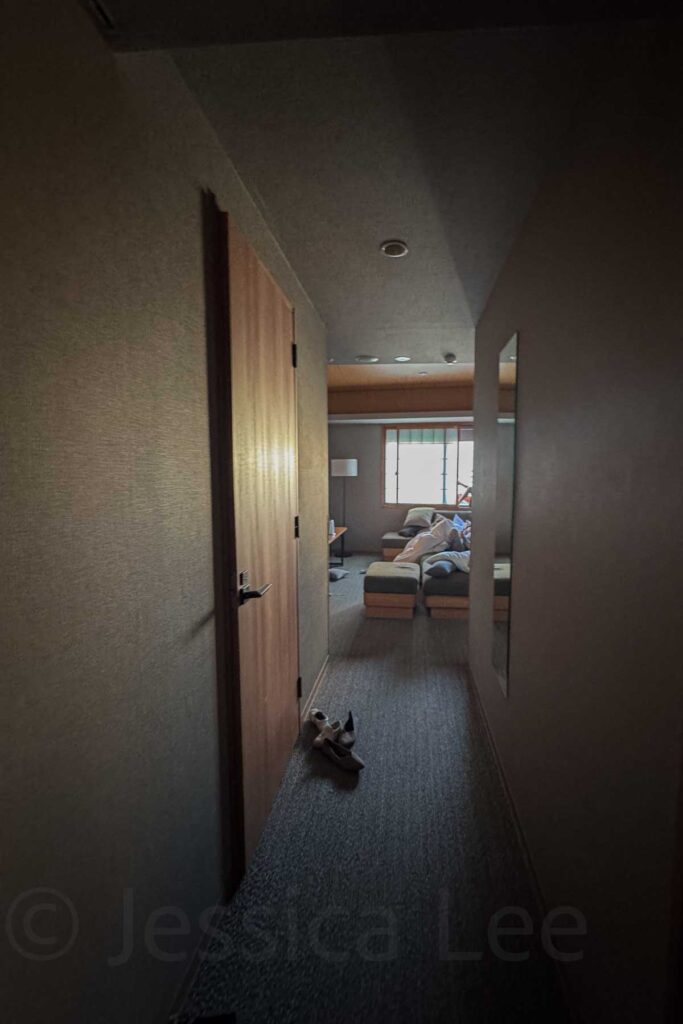 Dimly lit hallway leading to the living space of a Mimaru Suites Asakusa room, with shoes by the door. Reflects the home-like atmosphere ideal for family stays in Tokyo.