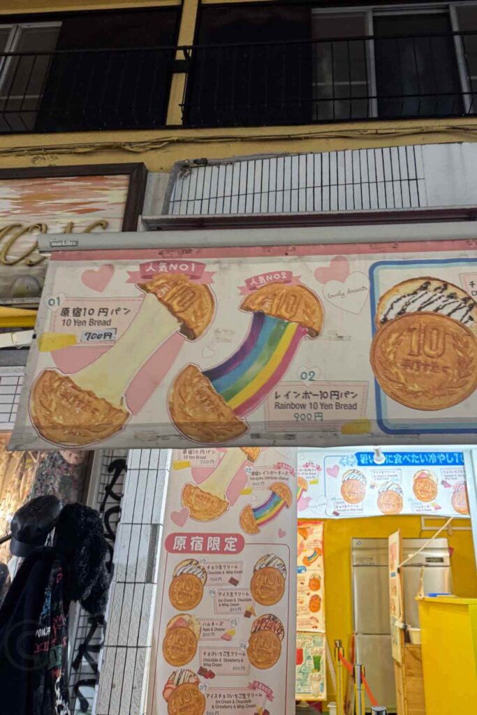 A colorful shop sign in Harajuku advertises cheesy stretchy 10 Yen Bread, including the popular Rainbow Yen Bread variation. This fun street snack is a quirky, Tokyo treat.