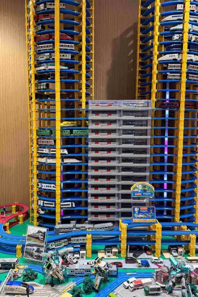 Intricate looping tall towers of plastic red and yellow and gray train tracks displayed in a toy train hobby shop in Tokyo station mall.