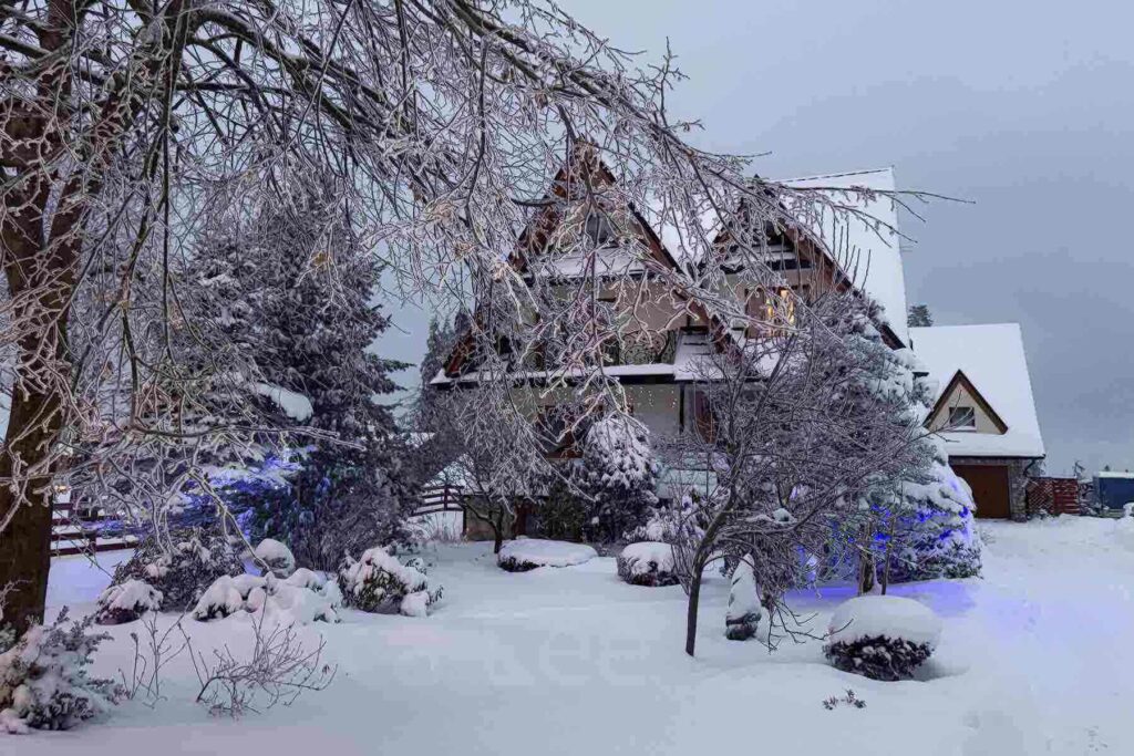 A cozy chalet in Zakopane, Poland nestled among snow‑covered trees and blanketed gardens, twinkling with subtle Christmas lights. A peaceful and charming escape for a magical Christmas holiday trip.