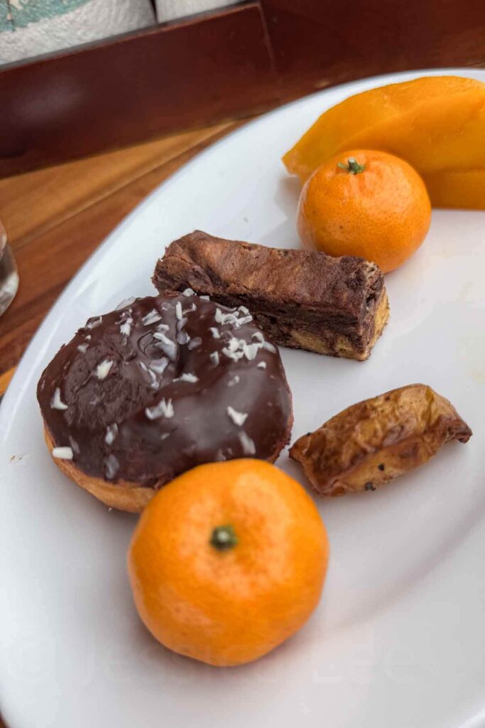 Plate of breakfast sweets and fruit including a chocolate-covered donut, marble sweet bread, tangerines, and sliced mango from the buffet at Hyatt Danang.