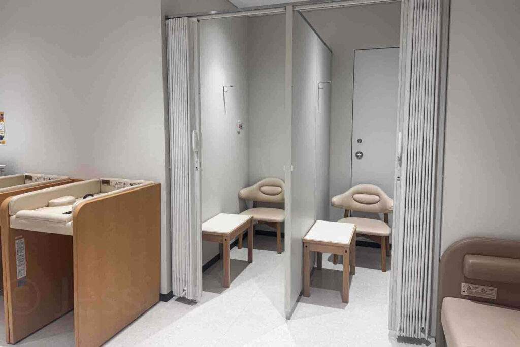 Clean indoor nursing room in Haneda airport in Japan with private cubicles chairs small tables and baby changing stations. Highlights why Japan is one of the easiest places to travel with a baby.