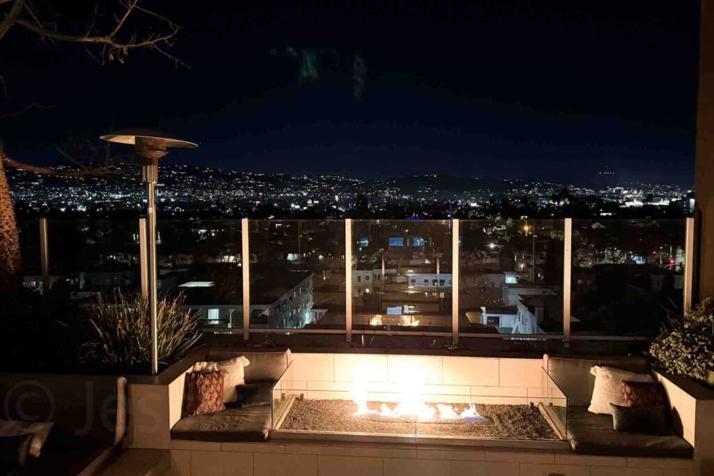 Centered view of a rooftop fire pit at Kimpton Hotel glowing against the sparkling Los Angeles skyline. A perfect spot for couples enjoying a staycation in the city.