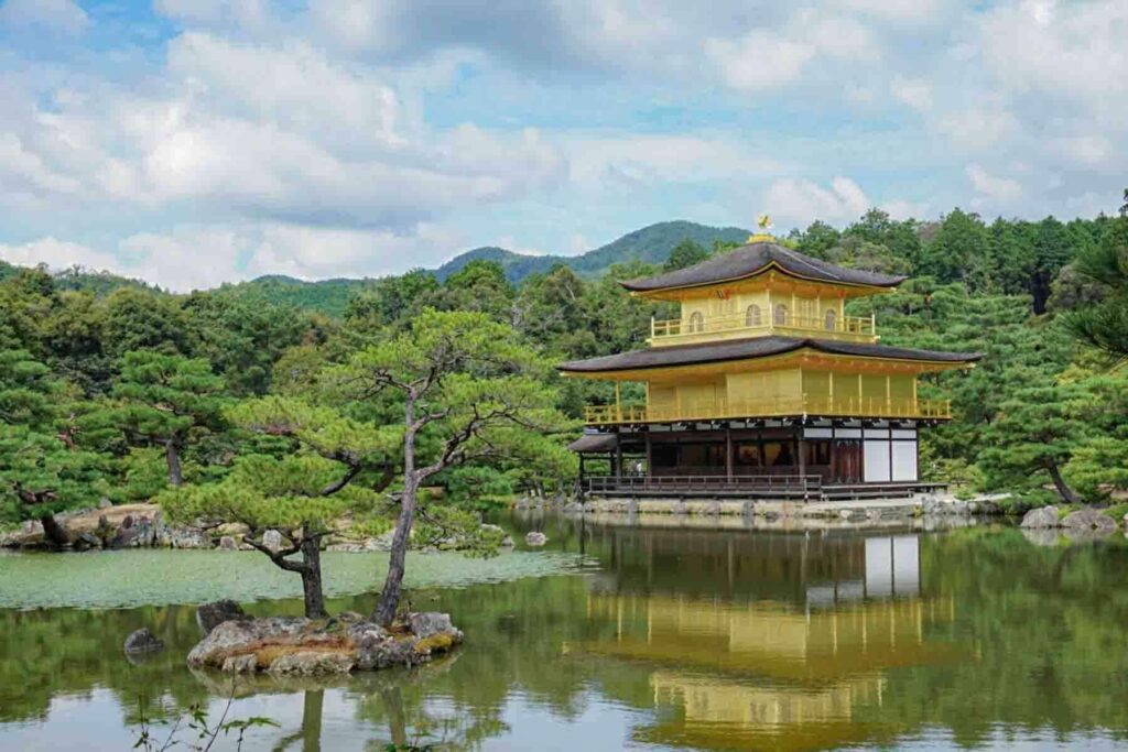 The Golden Temple main pavilion on a cloudy and bright blue day in Kyoto, Japan.