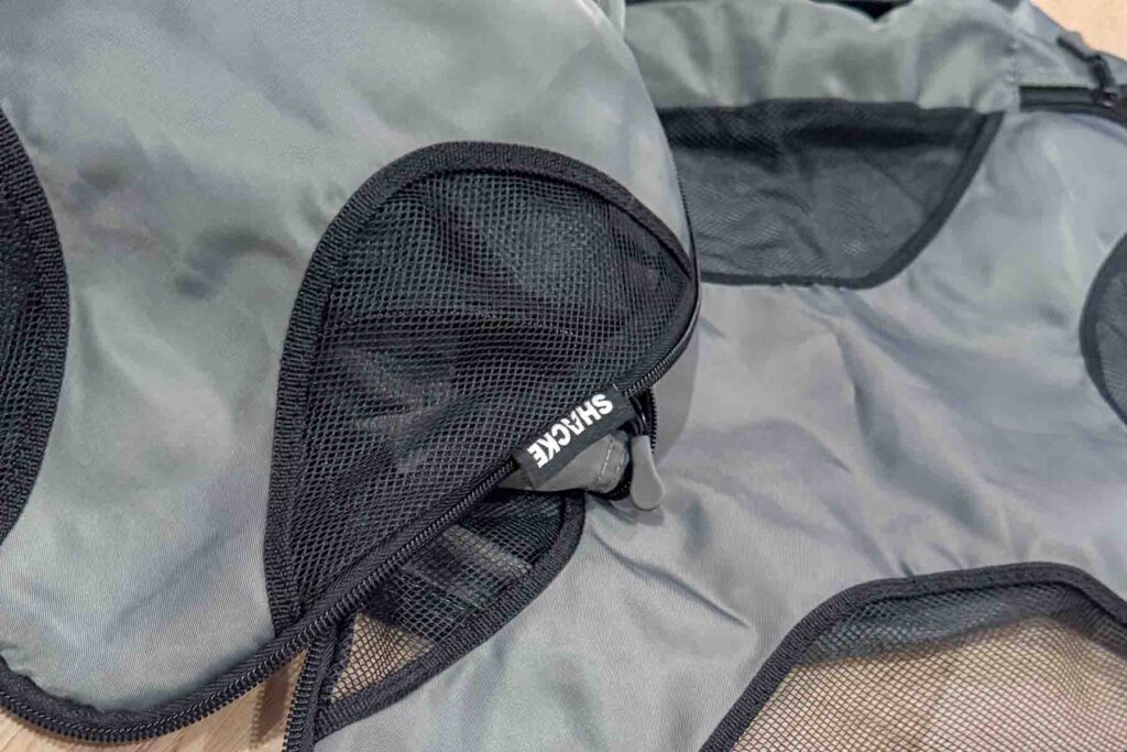 A close up of a gray and black mesh Shacke brand packing cube unzipped.