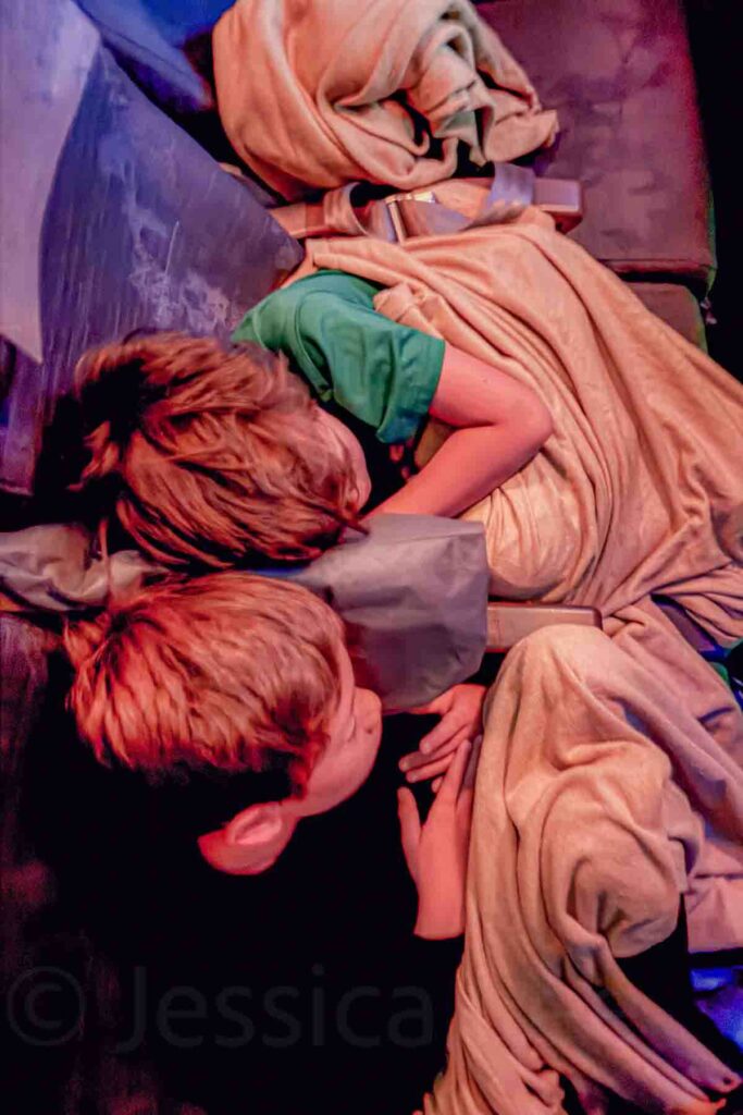 Two brothers sleep leaning against each other across airplane seats with blankets tucked around them. The peaceful moment shows how kids can settle in and adapt well during a long international flight.
