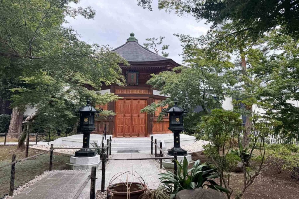 Traditional wooden temple hall, Jizodo, at Gotokuji Temple in Tokyo surrounded by trees and black lanterns. Quiet temple grounds can be a nice break from busy city days.