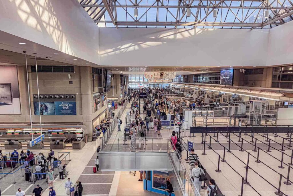 Crowds move through long lines in the large Bradley international terminal of LAX Airport. The busy terminal shows travelers preparing for international flights.