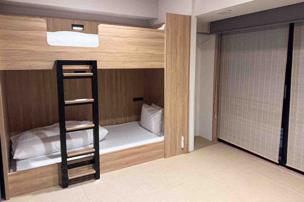 Family style hotel room with wooden bunk beds beside a tatami floor. Apartment style rooms like this can make a family trip to Japan much easier with more space.