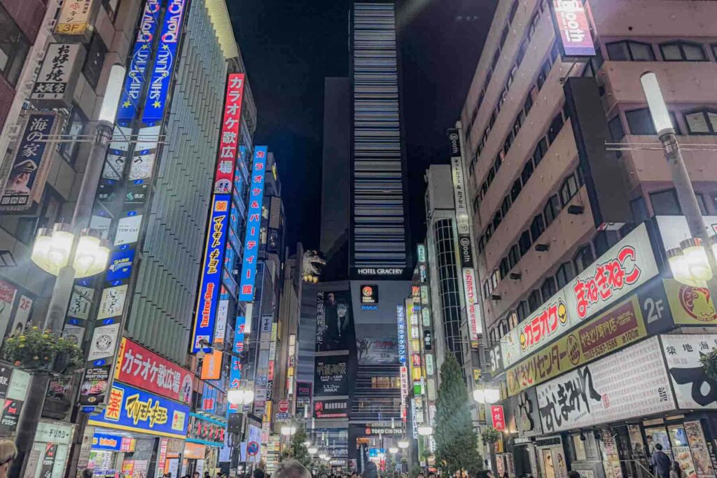 Bright vertical neon signs and busy sidewalks in Shinjuku at night. Entertainment districts like this offer unlimited restaurants and transit access for families traveling to Tokyo.