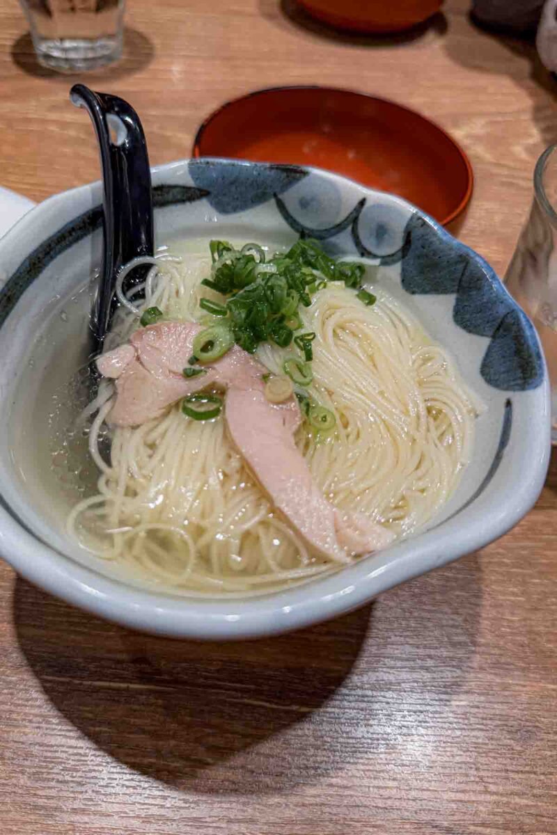 Small bowl of noodle soup with clear broth, sliced chicken, and green onions on top. A simple option that works well for picky eaters traveling to Japan.