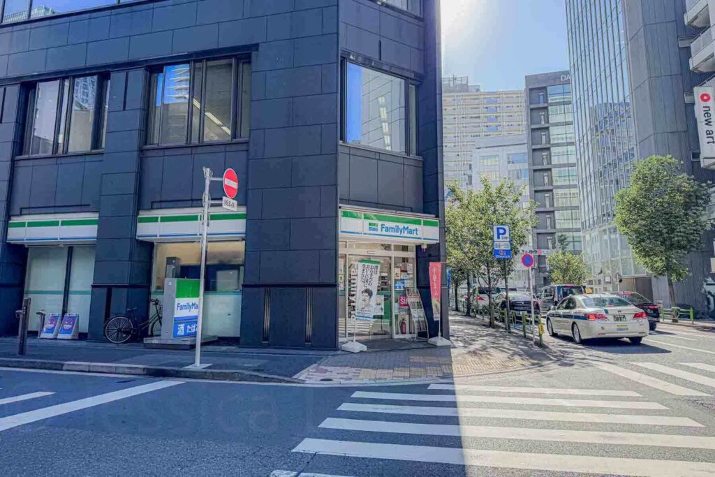 FamilyMart convenience store on a quiet Tokyo street corner with taxis and modern buildings nearby. Convenience matters when choosing where to stay in Tokyo with kids.