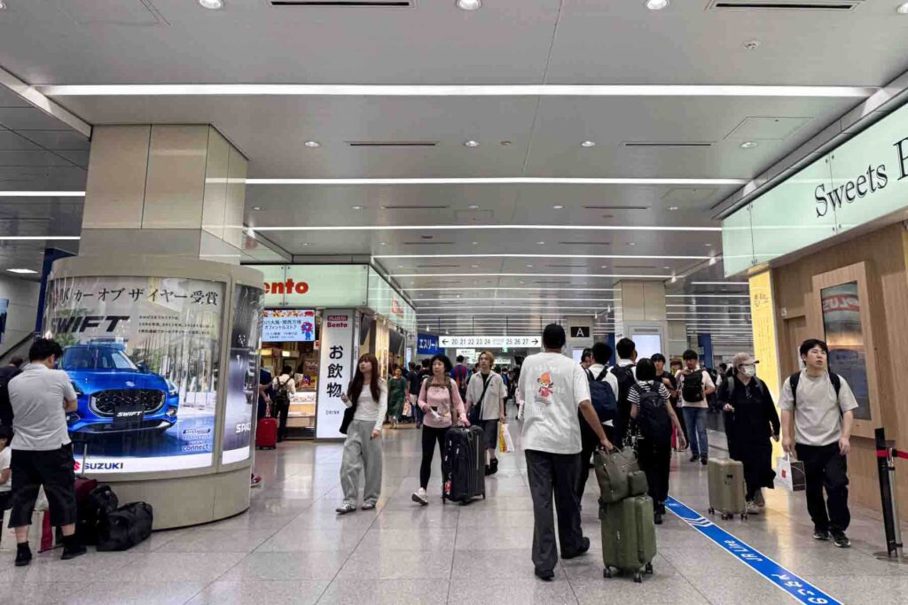 Busy hall inside Tokyo Station with travelers walking between shops and ticket areas rolling suitcases. Major stations like this are a normal part of traveling to Japan.