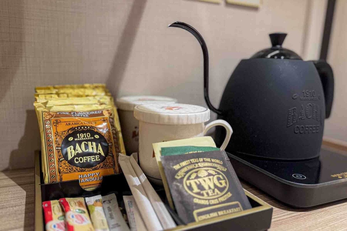 A stateroom beverage station with a black kettle, mugs, TWG tea, and Bacha coffee sachets neatly arranged on a tray. This setup shows practical in-room amenities on a Disney cruise.
