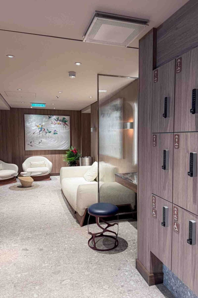 A quiet spa locker room features wooden lockers, soft seating, and a calm lounge area with neutral decor. This space highlights relaxation amenities available for adults on a Disney Adventure cruise.