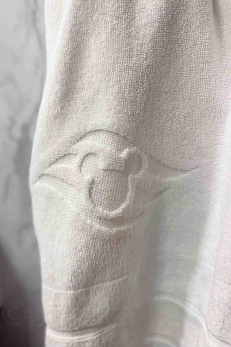 A close up of a white towel folded with a Mickey-mouse shape face hangs neatly on a towel bar. This detail highlights the signature Disney cruise room service touch.