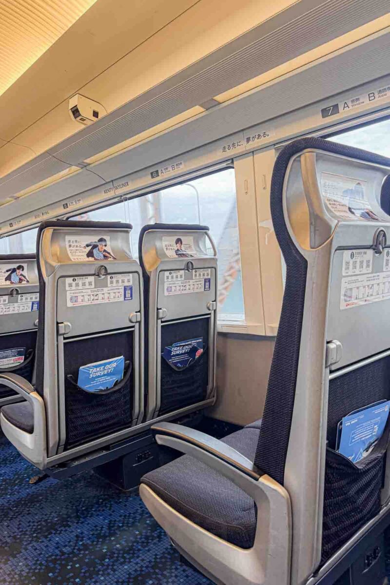 Comfortable forward facing seats inside the Skyliner airport express train with tray tables and large windows. This clean and spacious option makes getting into Tokyo from the airport with kids easy.