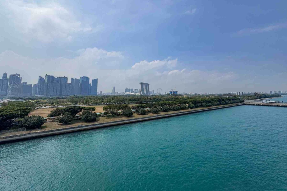 A wide view of Singapore’s skyline shows modern skyscrapers, Marina Bay Sands, and the waterfront under a blue sky. This scenic view highlights the embarkation port experience on the Disney Adventure cruise.