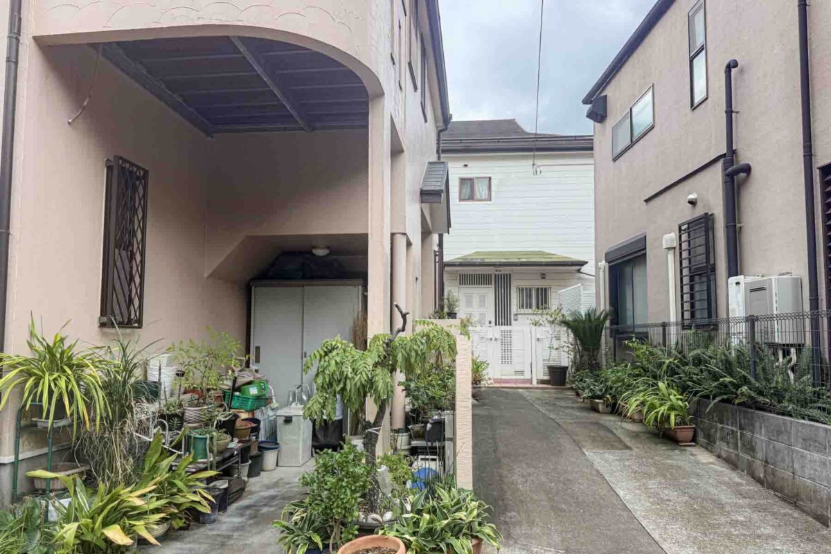 Quiet residential lane in Tokyo lined with compact houses, potted plants, and small gardens along the walkway. Peaceful neighborhoods like this show a different side of a Tokyo trip beyond the busy tourist districts.