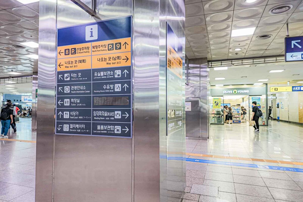 A large information sign inside Busan Station points toward "On board Parking". "North Port Parking". "Way out". "Platforms". "Tourist Information Center". "Nursing Room". "Toilet". "Food Court". "Meeting Room". "Elevator". "Coin Locker". The family facilities and clear directions can make arriving in Busan with children and luggage easier.