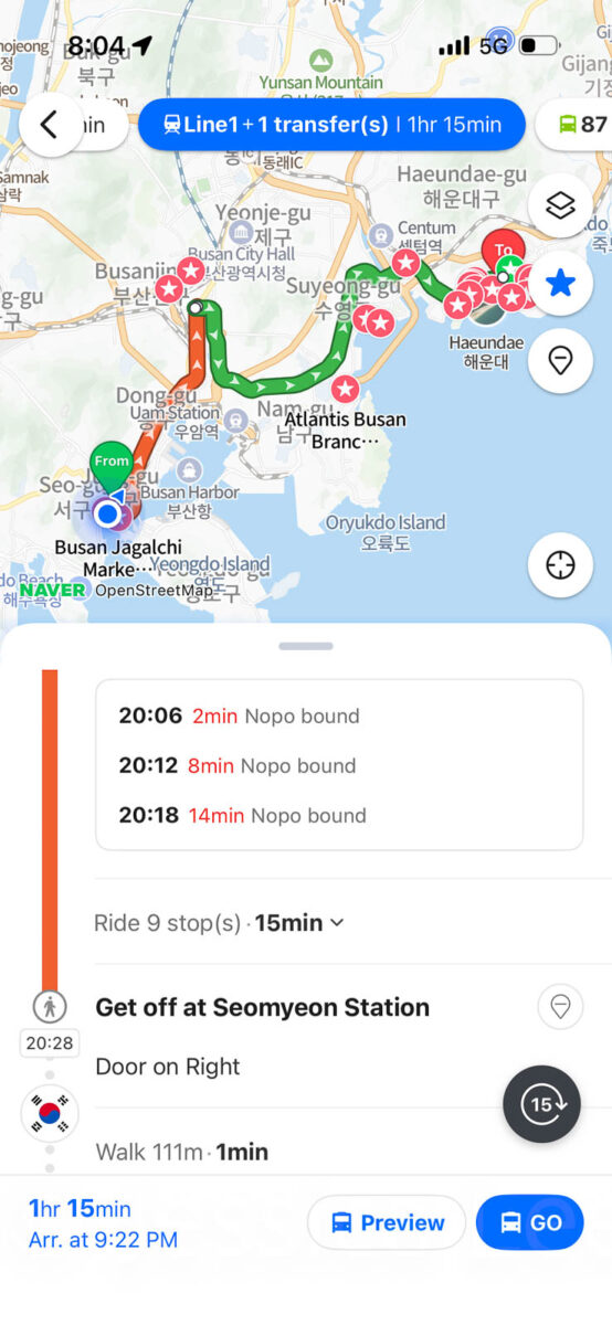 Naver Map displays a public transportation route across Busan with a Metro transfer at Seomyeon Station. The screen reads "Line1 plus 1 transfer 1hr 15min". "20.06 2min Nopo bound". "20.12 8min Nopo bound". "20.18 14min Nopo bound". "Ride 9 stops 15min". "Get off at Seomyeon Station". "Door on Right". "Walk 111m 1min". "1hr 15min". "Arr. at 9.22 PM". "Preview". "GO".