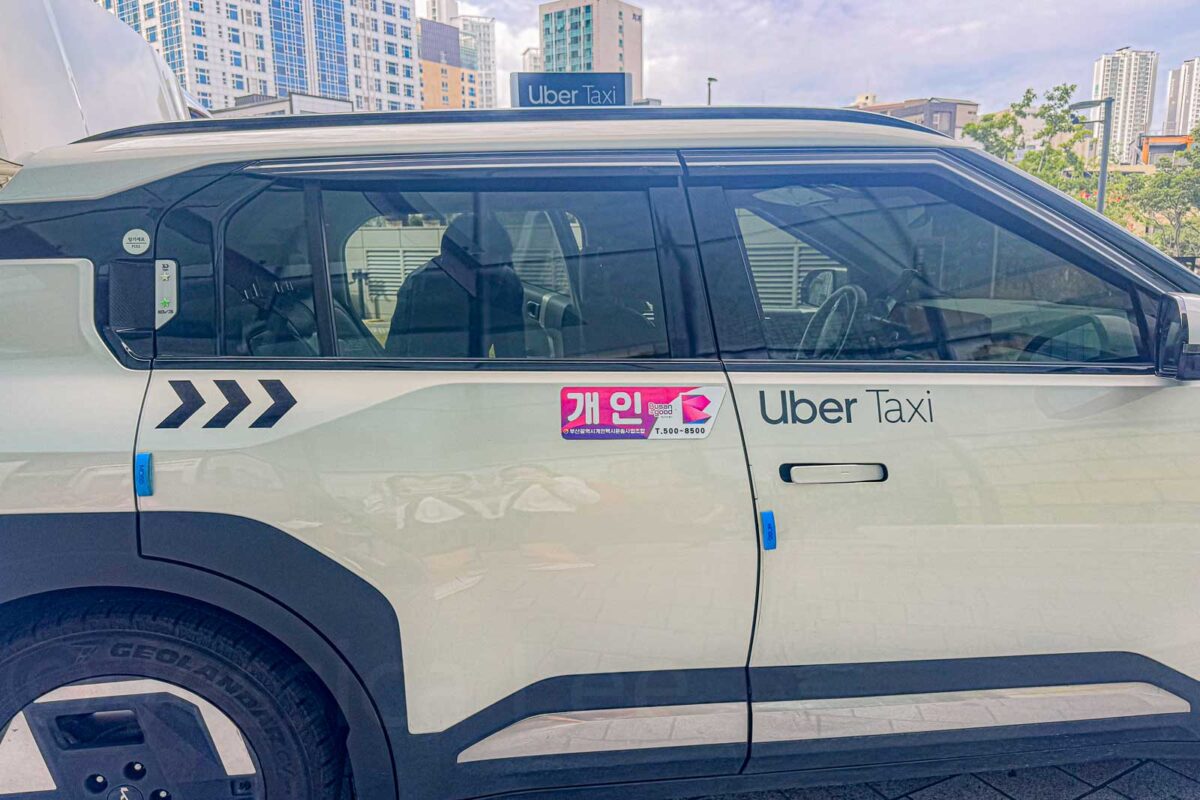 A white SUV style taxi parked in Busan has "Uber Taxi" displayed on the roof and side of the vehicle. Uber connects travelers with local taxis and can provide a useful alternative when public transportation is inconvenient with children.